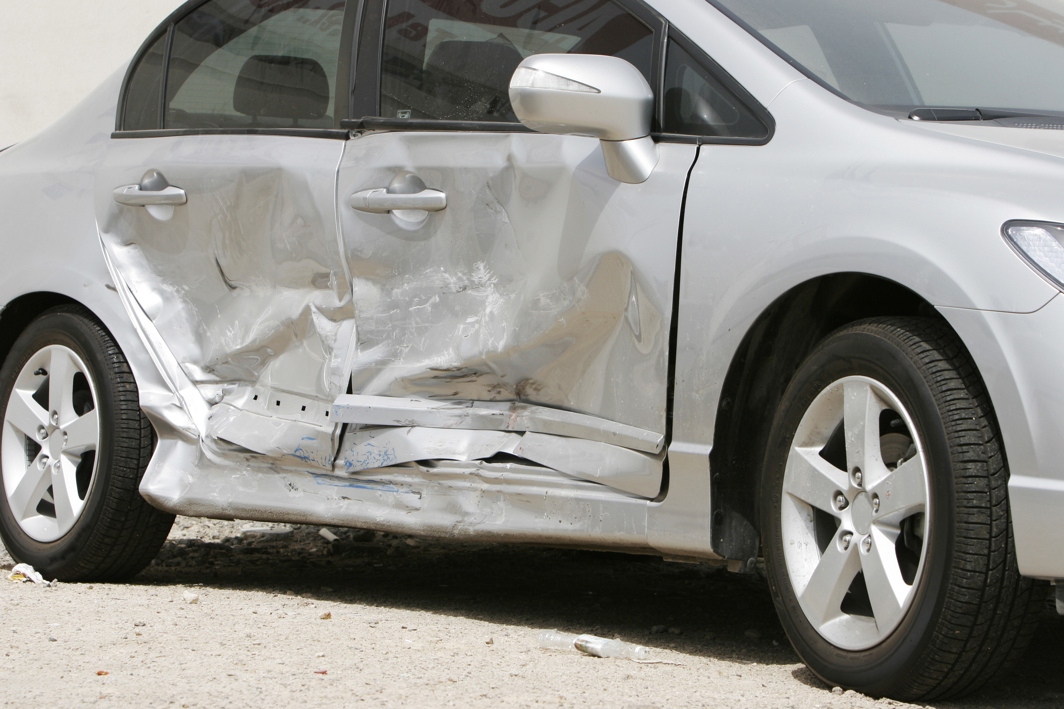 A silver sedan with side impact damage in need of side impact collision repair in Colorado Springs